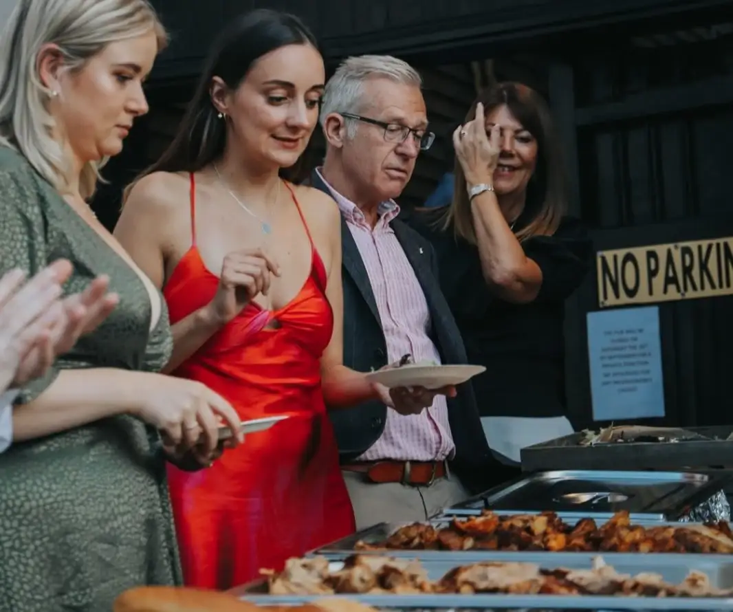 A woman wearing a red dress with her family creates a memorable graduation party with a catering experience that’s delicious.