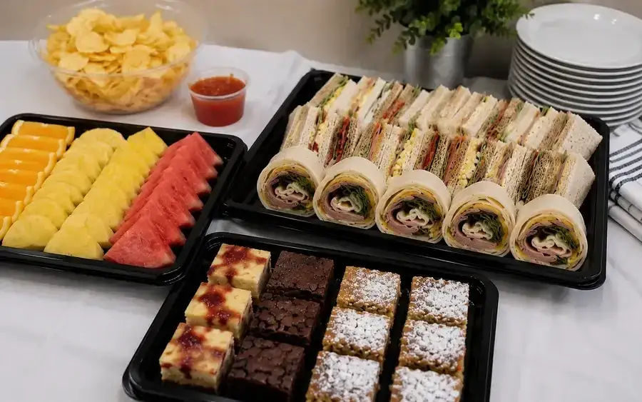 Buffet table set with sandwich platters, savouries and bowls of salad